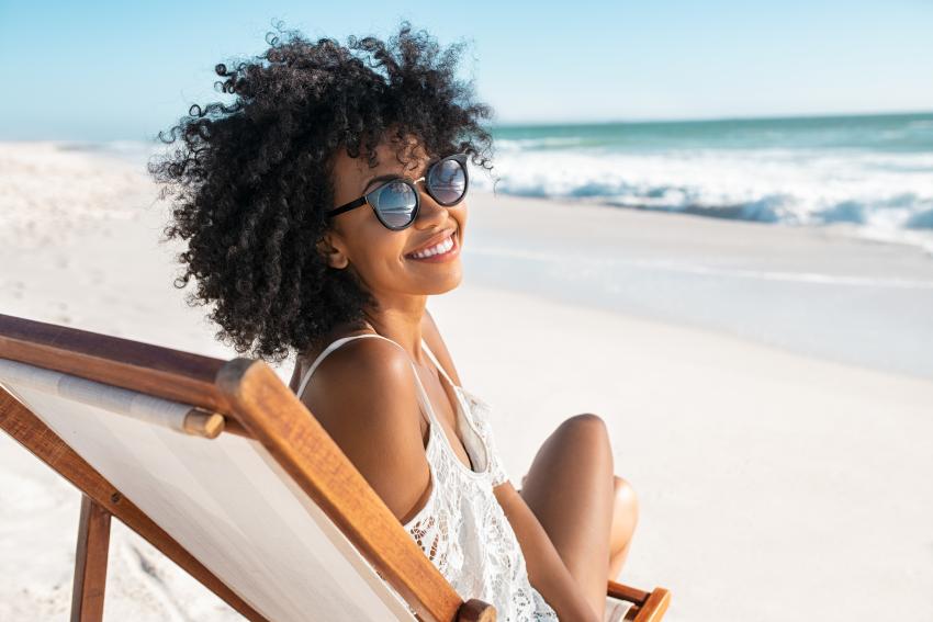 Junge Frau entspannt auf einem Liegestuhl am Strand – Symbolbild für Sommerurlaub, Erholung und die Urlaubstage, auf die Lehrlinge laut Gesetz Anspruch haben.