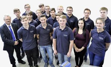 Blick in eine moderne Lehrwerkstätte mit mehreren Maschinen und jungen Menschen bei der Arbeit – Ausbildungsumfeld für angehende Mechatroniker:innen.